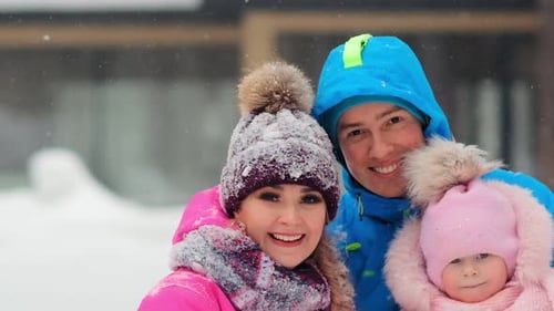 Happy Family Poses for Camera Standing on White Snow