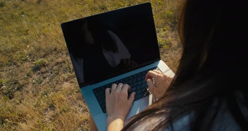 Woman Types on Laptop in Rural Outdoor Setting