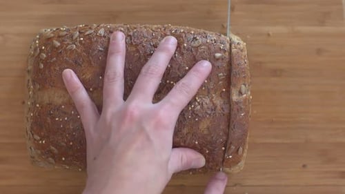 Hand Slicing Fresh Seeded Bread Loaf