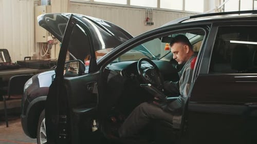 Mechanic Using Tablet Inside Car at Repair Shop