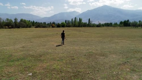 Man Walks Through Grassy Field on Sunny Day