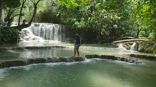 Man Walking Barefoot by Tropical Waterfall