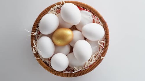 Close-up of a basket filled with chicken eggs. White and a golden one.