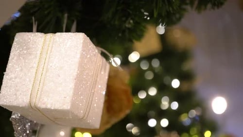 Close Up Shot of White Gift Box with Christmas Tree and Ornaments in the Background