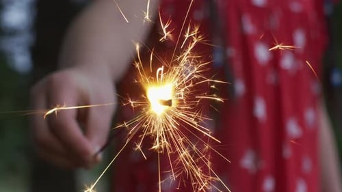Child Holds a Sparkling Golden Sparkler Outside