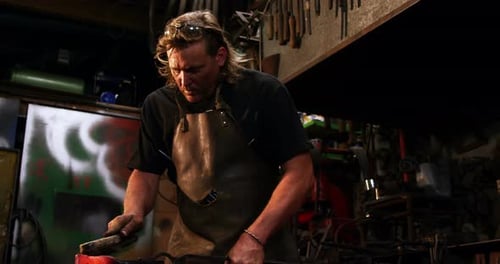 Blacksmith using wire brush on hot iron