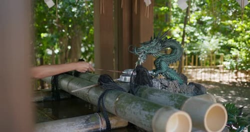 Woman wash hand before enter Japanese temple