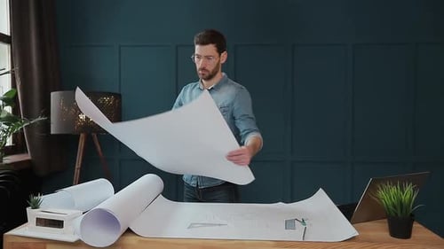 Nahaufnahme eines jungen Mannes in der Hand eines Ingenieurs, der das Papier öffnet und die Konstruktionszeichnungen überprüft