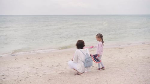 Madre con su hijo pequeño soplando pompas de jabón en la playa del mar viajando con un niño en familia en verano