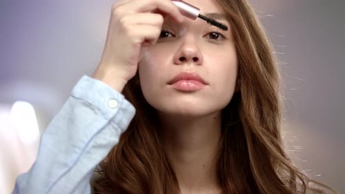 Frau trägt Wimperntusche auf Wimpern auf. Mädchen beim Auftragen von Beauty Make Up