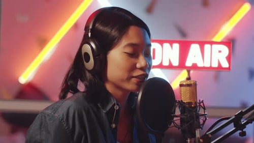 Asian Female Radio Host Speaking into Mic in Home Studio