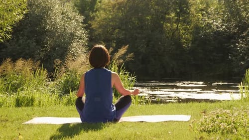 Woman practicing yoga outdoors. Meditation at sunrise. Female meditating in park