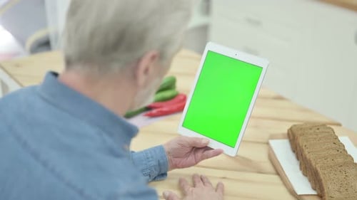 Rear View of Old Man Looking at Tablet with Chroma Key Screen