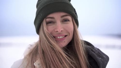 Portrait of a Cheerful Woman Throwing Snow Up Smiles at the Camera