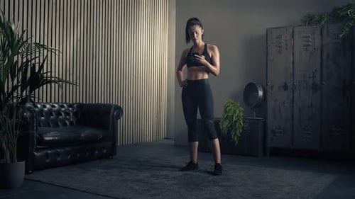 Fit Woman Checking Phone in Gym Interior