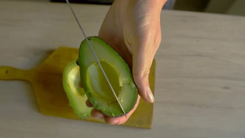 White woman cutting avocado. Caucasian female preparing healthy meal at home. Top view of young girl