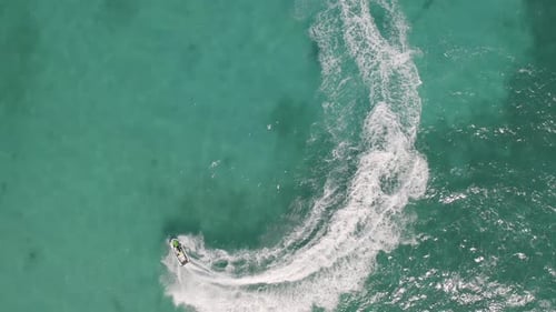 Aerial top view of jet ski or boat drawing a shape on sea ocean turquoise water. Adventure