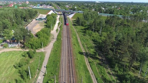 Der elektrische Personenzug fährt in die Ferne und fährt unter der Automobilbrücke vorbei