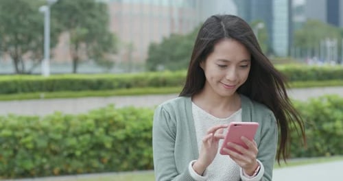 Woman Using Phone in Urban Park Setting