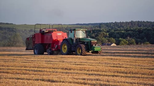 Traktor mit Heuballen auf Anhänger. Luftaufnahme des Traktors mit Heu im Feld