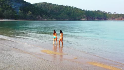 Pretty smiling ladies on vacation spending quality time at the beach on paradise white sand and blue