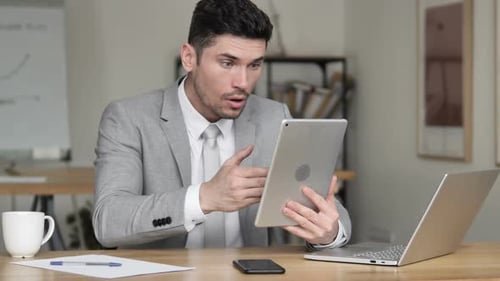 Man Shocked by Information on Tablet in Office
