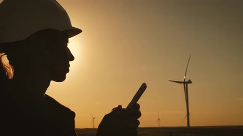 Silhouette Female Engineer Working in Wind Turbine Electricity Industrial at Sunset.