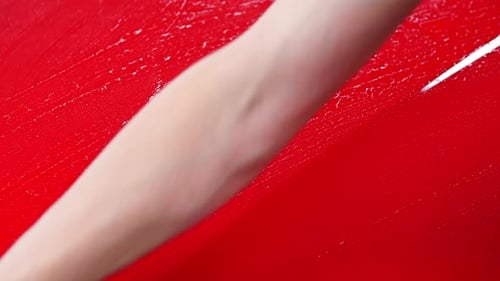 Car Washing Service Man Wipes Water From a Red Car Surface with Rag
