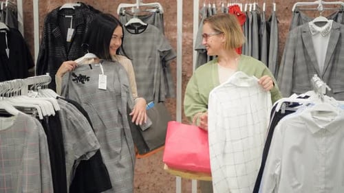 Stylist Selects a Set of Casual Clothes To Women in a Store at Shopping Mall