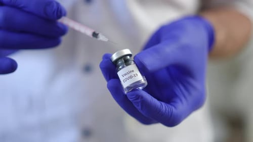 Männliche Hände füllen Spritze mit Covid19-Impfstoff in Zeitlupe Nahaufnahme