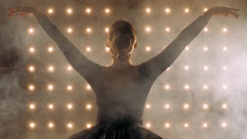 Silhouette of Ballerina in Black Dress Is Dancing Ballet in the Dark Studio.