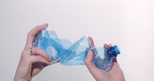 Hands crushing a blue plastic water bottle