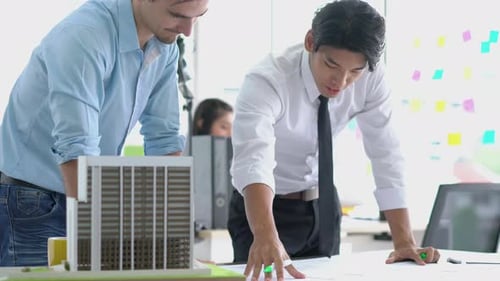 Architects working blueprint and building model