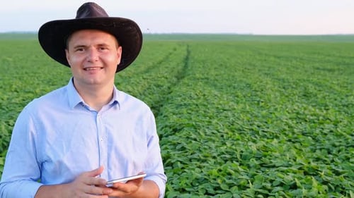A Young Agronomist Studies Plants in a Field and Uses a Tablet