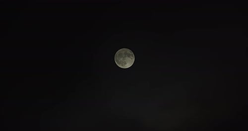 Wide shot of a full moon as fog passes by revealing full moon at the end.