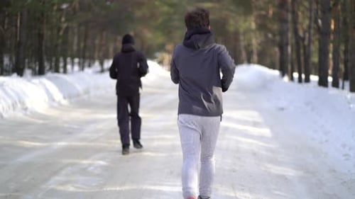 Two People Running on Snowy Winter Path