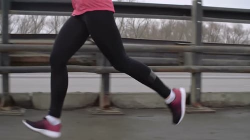 Female Runner Training for Marathon on Bridge
