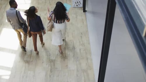 Diverse group of business people working together, walking, discussing work in modern office