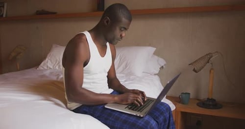 Man Working on Laptop in Bedroom