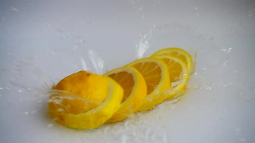 Slices of Lemon Falling Into Water