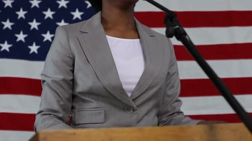Woman Giving Speech with American Flag Backdrop
