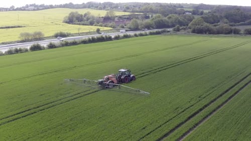 Tractor Spraying Crops in Green Rural Field