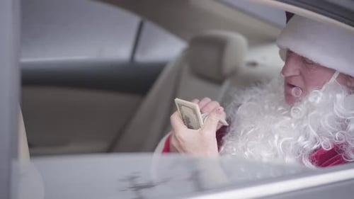 Old Santa Claus Sitting in the Car on Back Seat, Taking Off the False Beard, Licking Finger and