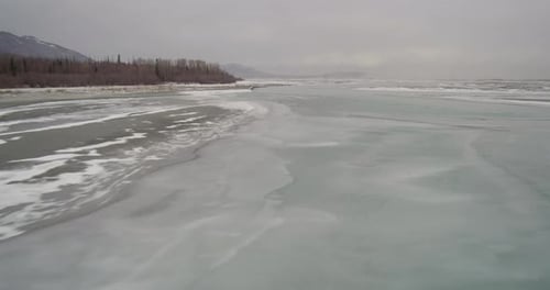 Aerial helicopter wide shot, pan across snowy Alaskan valley, drone footage