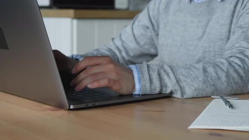 Female hands typing on laptop at desk, close up view