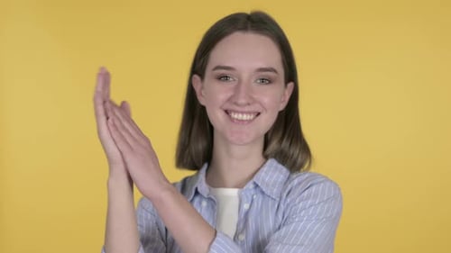 Woman Smiling and Clapping on Yellow Background