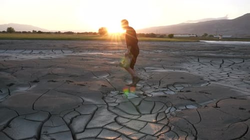 Man Walks on Cracked Earth at Sunrise