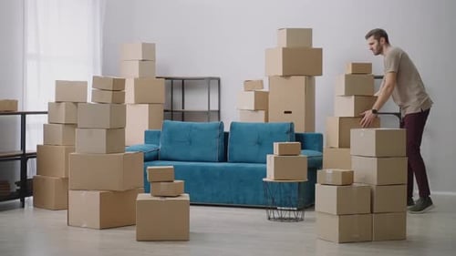 Man Stacking Moving Boxes in Living Room