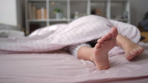 Closeup View of Feet Lying on Soft White Pillow at Bed