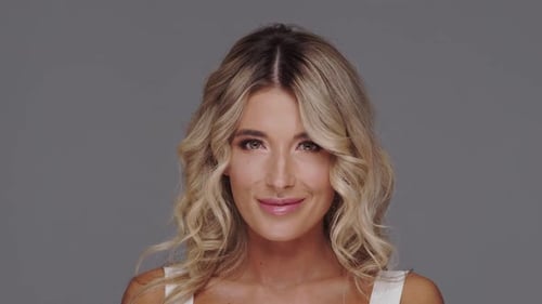 Studio portrait of young and beautiful blond woman over grey background.
